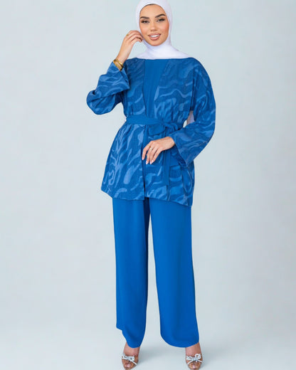 Woman wearing a blue patterned top and matching pants on a white background