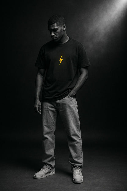 Man wearing a black t-shirt with a yellow bolt design on a dark background