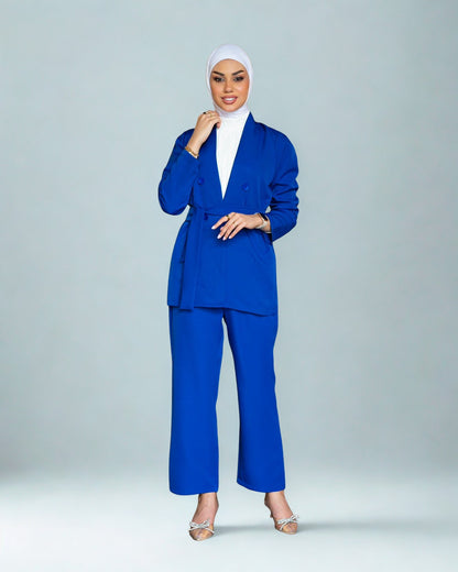 Woman wearing a blue suit with a white hijab on a gray background
