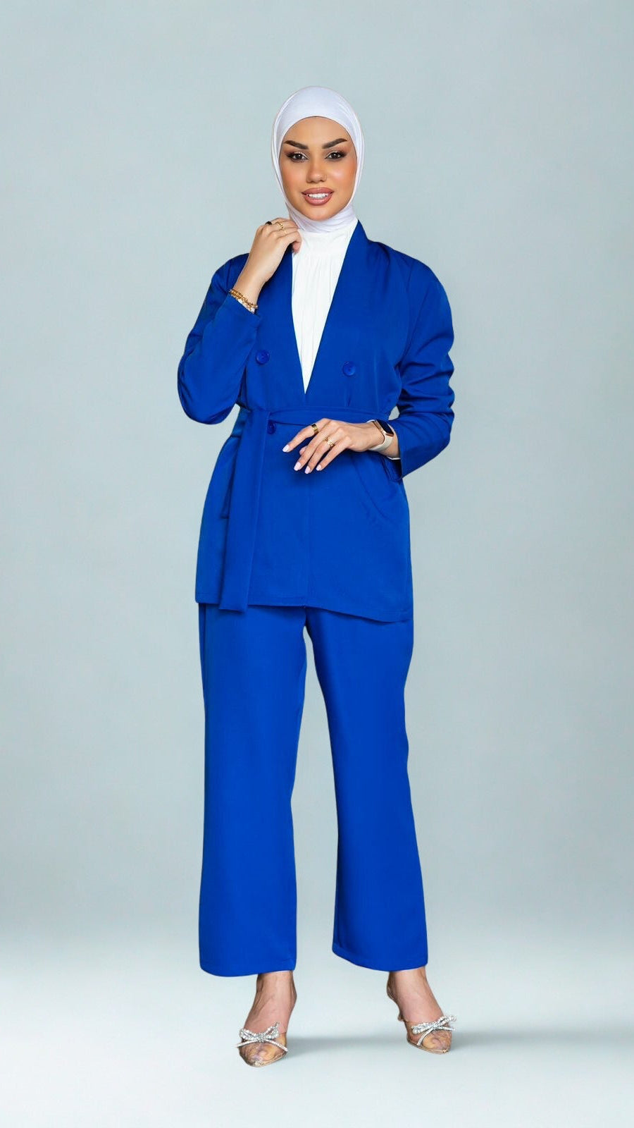 Woman wearing a blue suit with a white hijab on a gray background