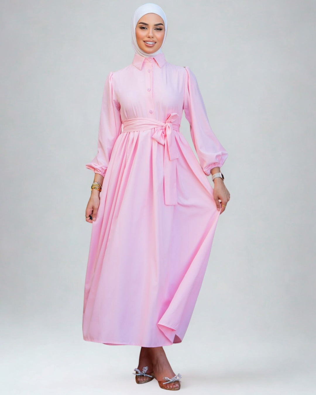 Woman wearing a pink dress with a belt on a white background