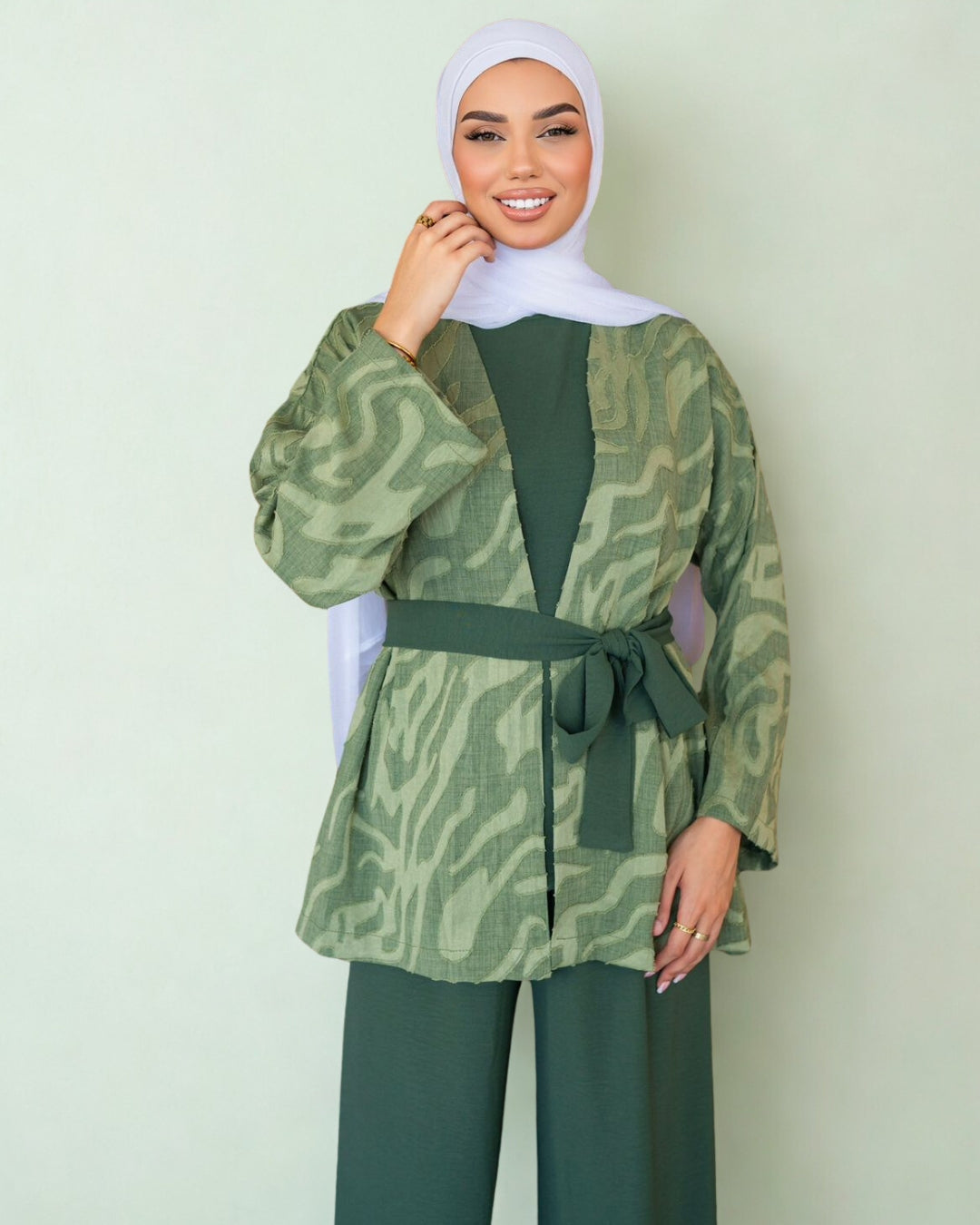 Woman wearing a green patterned top and matching pants against a light green background