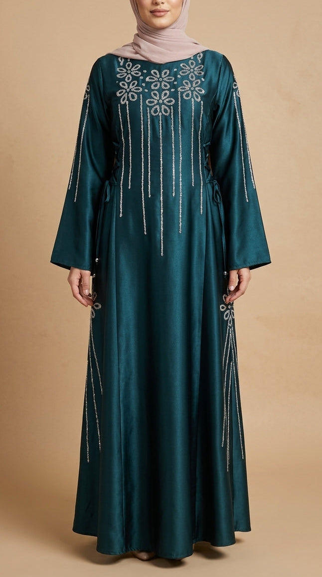 Teal abaya with embroidery on a beige background