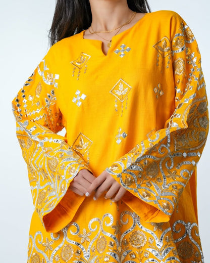 Yellow embroidered traditional outfit with intricate patterns on a white background