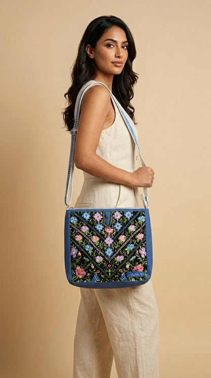 Woman holding a blue embroidered bag against a beige background