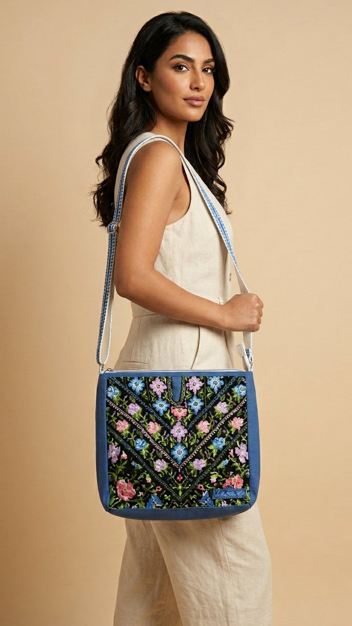 Woman holding a blue embroidered bag against a beige background