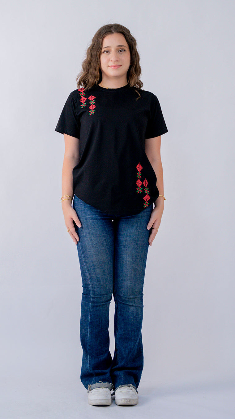 Person wearing a black t-shirt with red floral patterns and blue jeans on a white background
