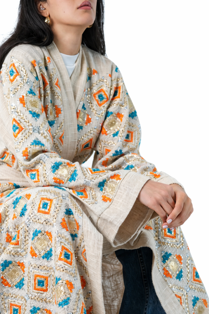 Woman wearing a patterned shawl with geometric designs on a white background