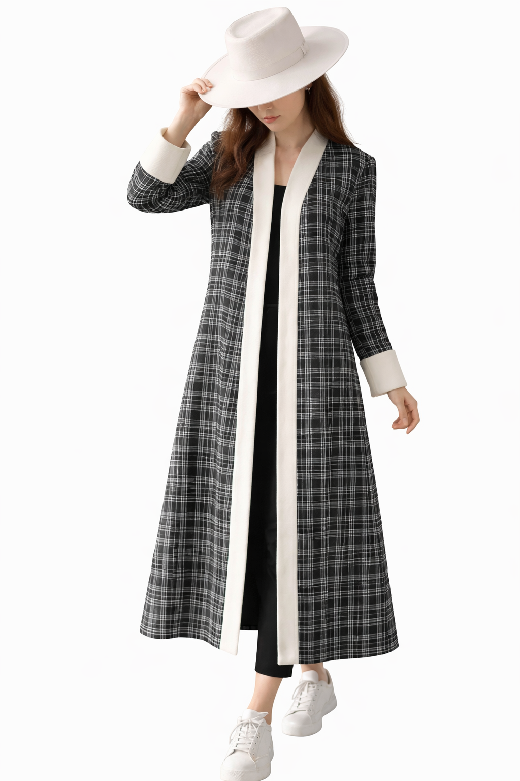 Woman wearing a long black and white checkered coat with a white hat on a white background