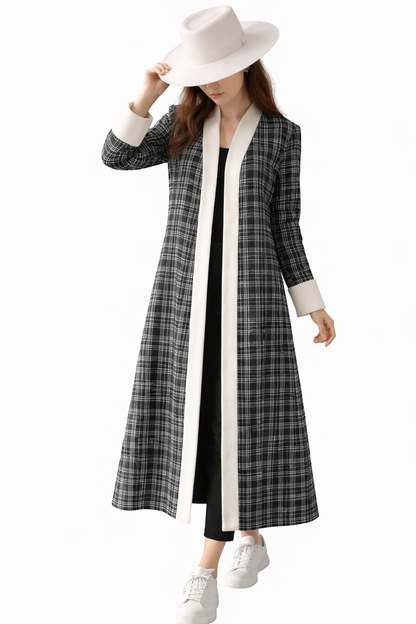 Woman wearing a long black and white checkered coat with a white hat on a white background