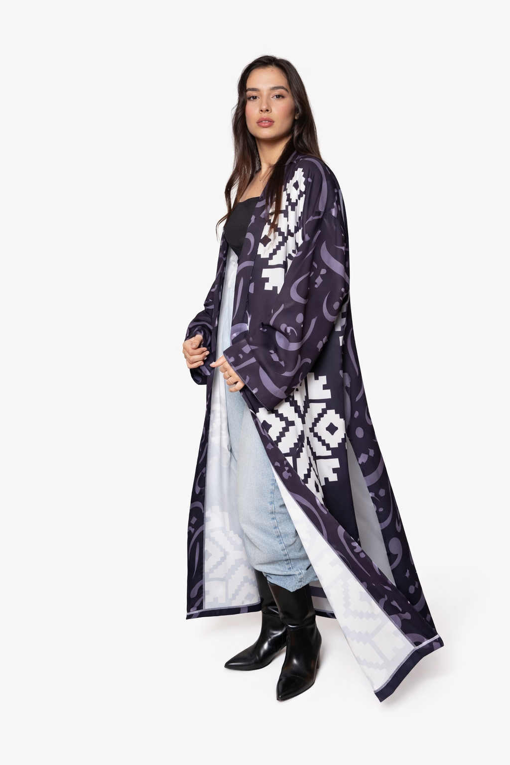 Woman wearing a long, dark purple patterned coat over a light blue dress on a white background