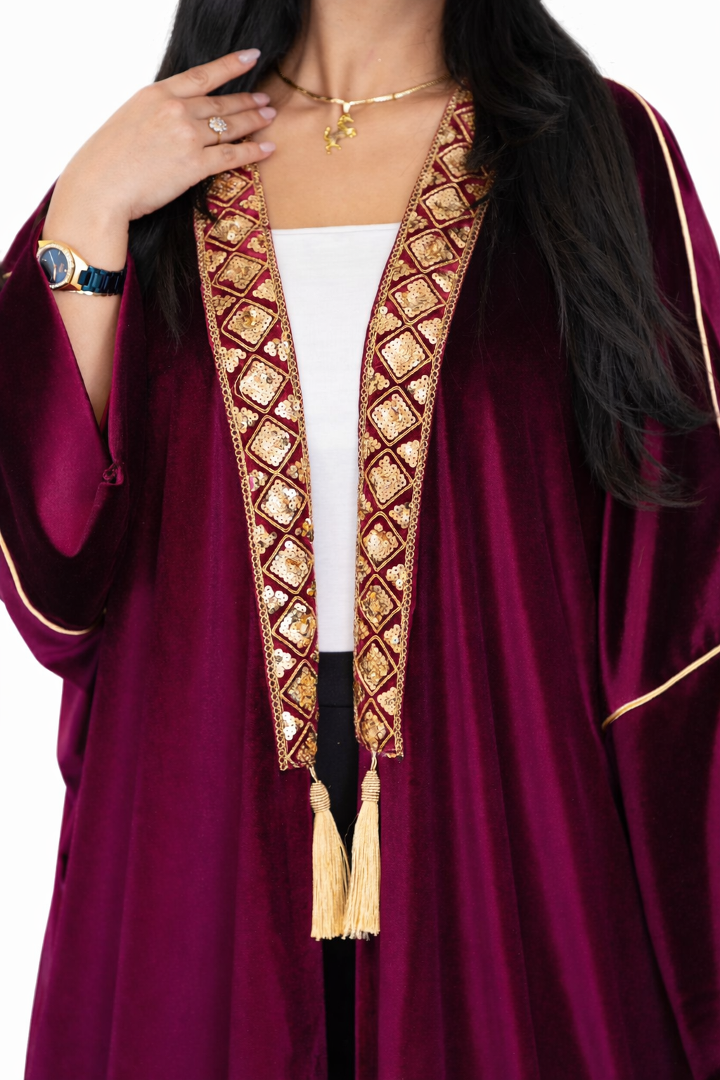 Magenta abaya with gold embroidery and tassels on a white background