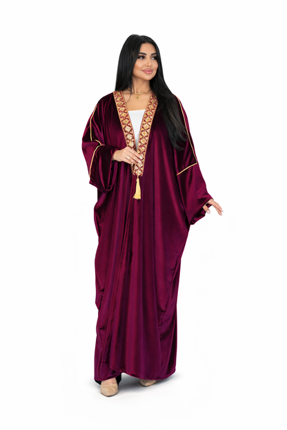 Woman wearing a burgundy abaya with gold trim on a white background