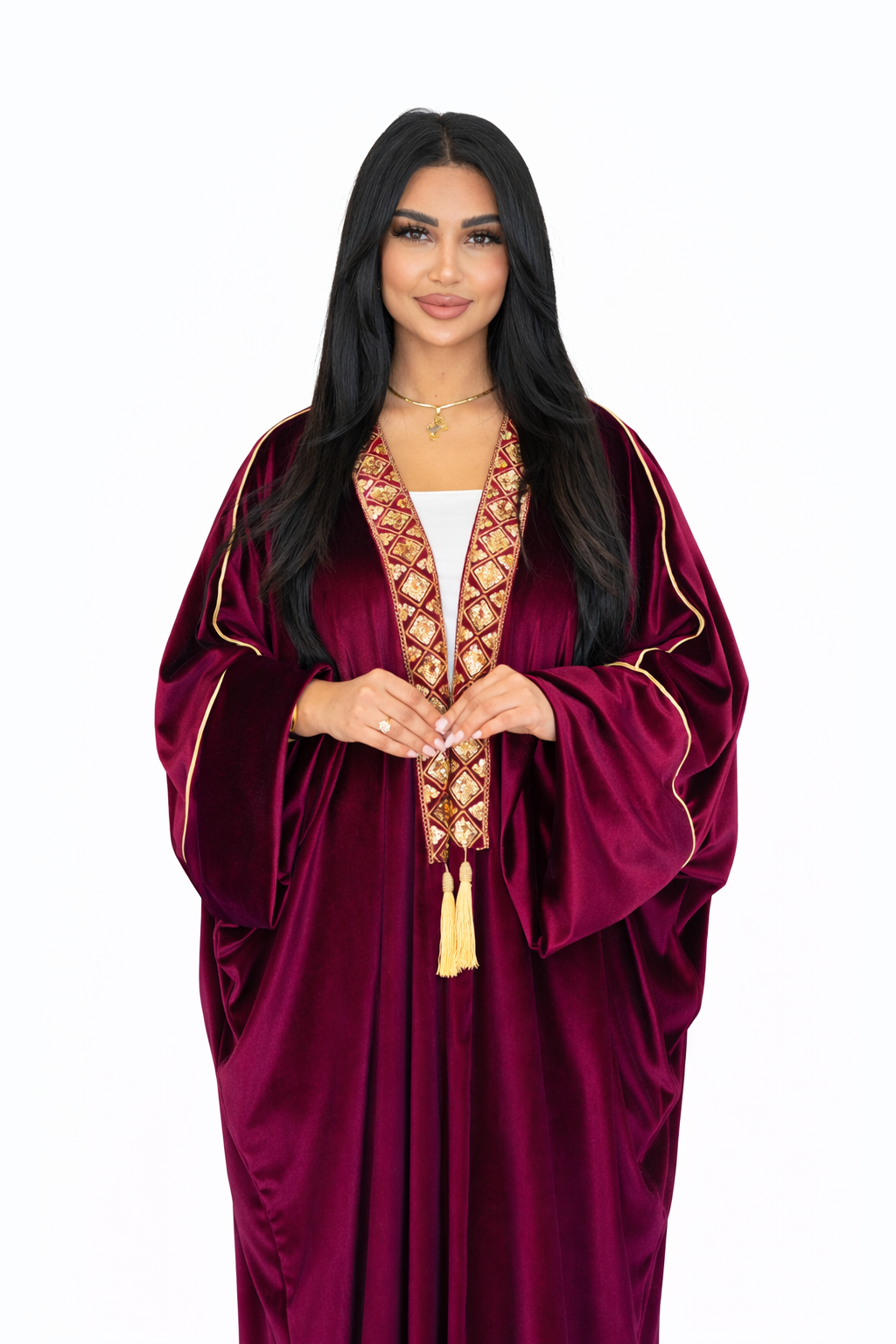 Woman wearing a burgundy abaya with intricate gold embroidery on a white background