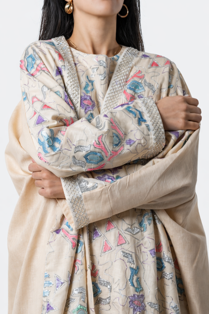 Woman wearing a beige dress with colorful patterns on a white background