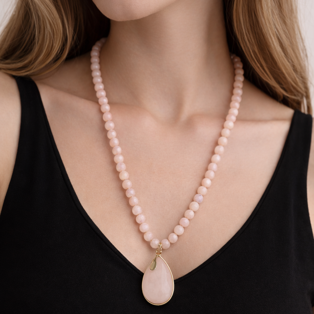 Woman wearing a pink beaded necklace with a large pink pendant.