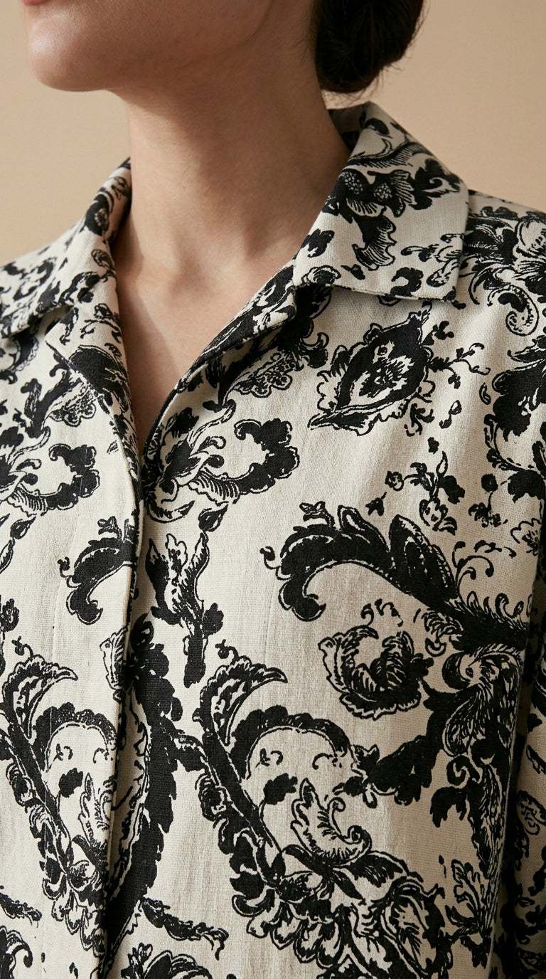 Close-up of a person wearing a black and white patterned shirt against a beige background