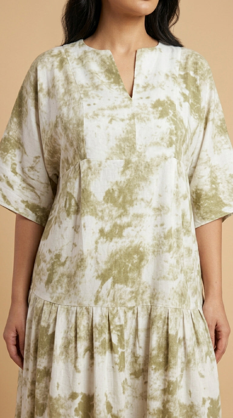 Woman wearing a green and white patterned dress against a beige background
