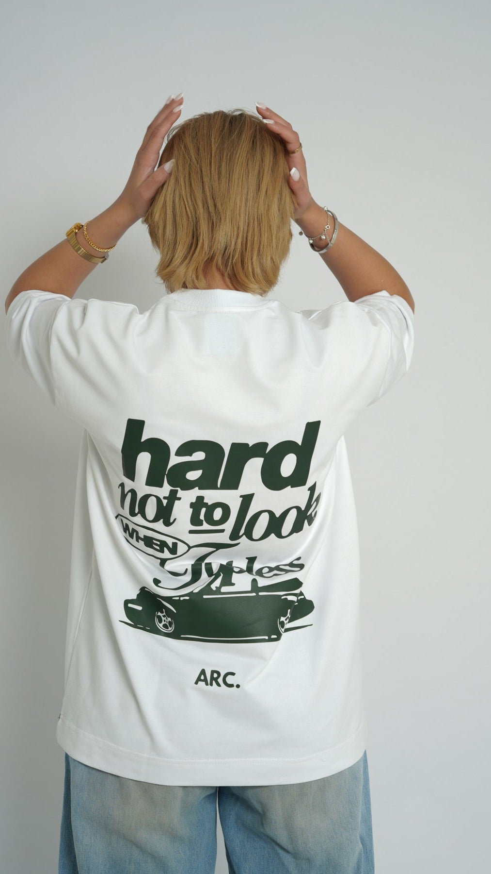 Person wearing a white t-shirt with text and graphics on the back, standing against a plain background.