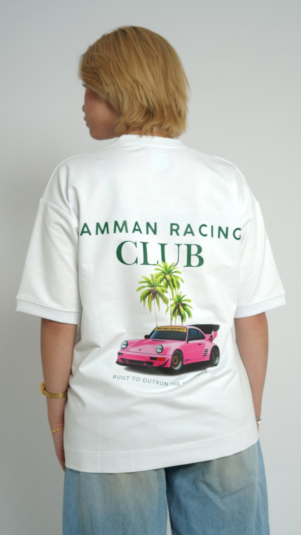 Person wearing a white t-shirt with 'Amman Racing Club' design on the back.