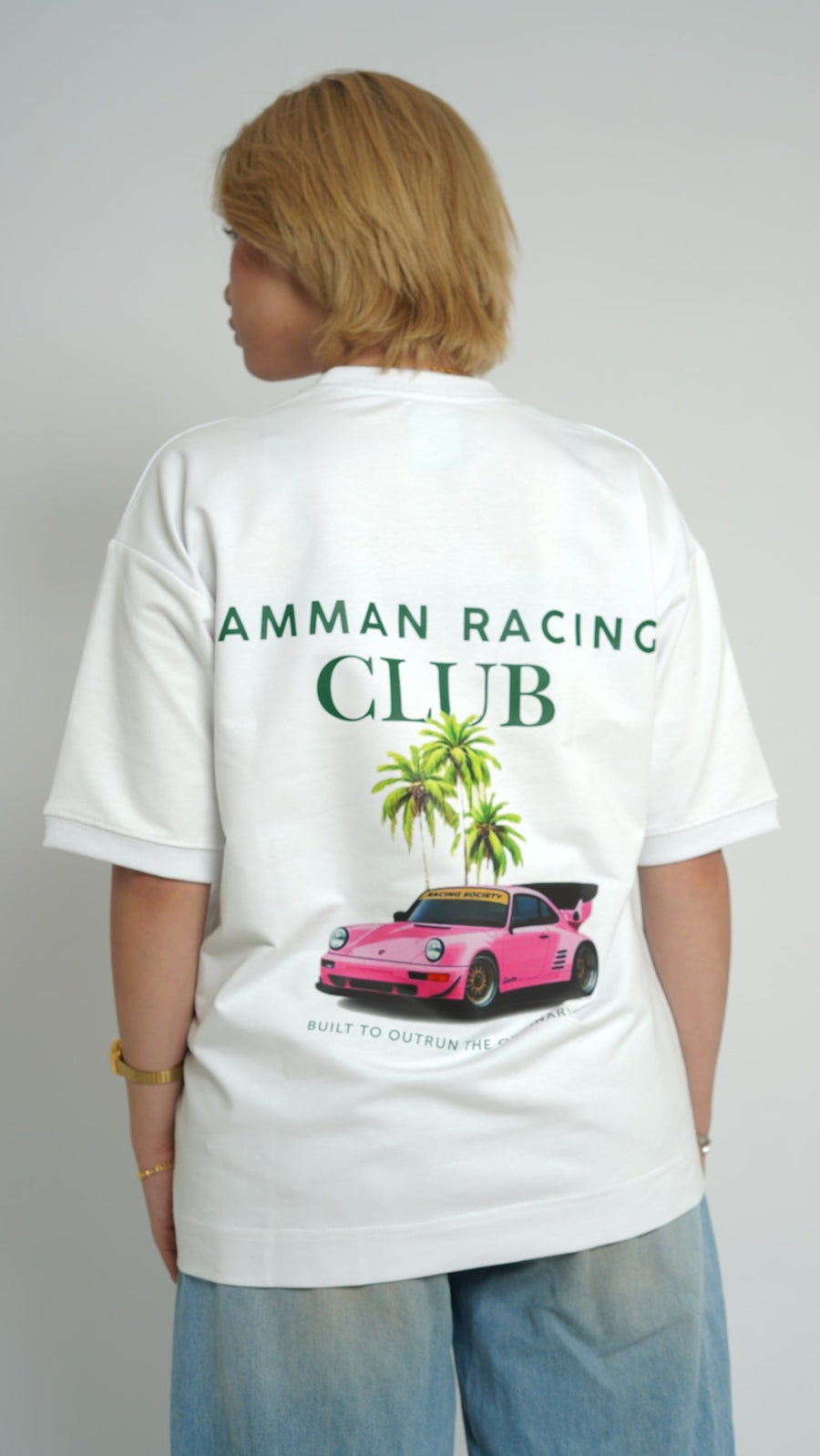 Person wearing a white t-shirt with 'Amman Racing Club' design on the back.