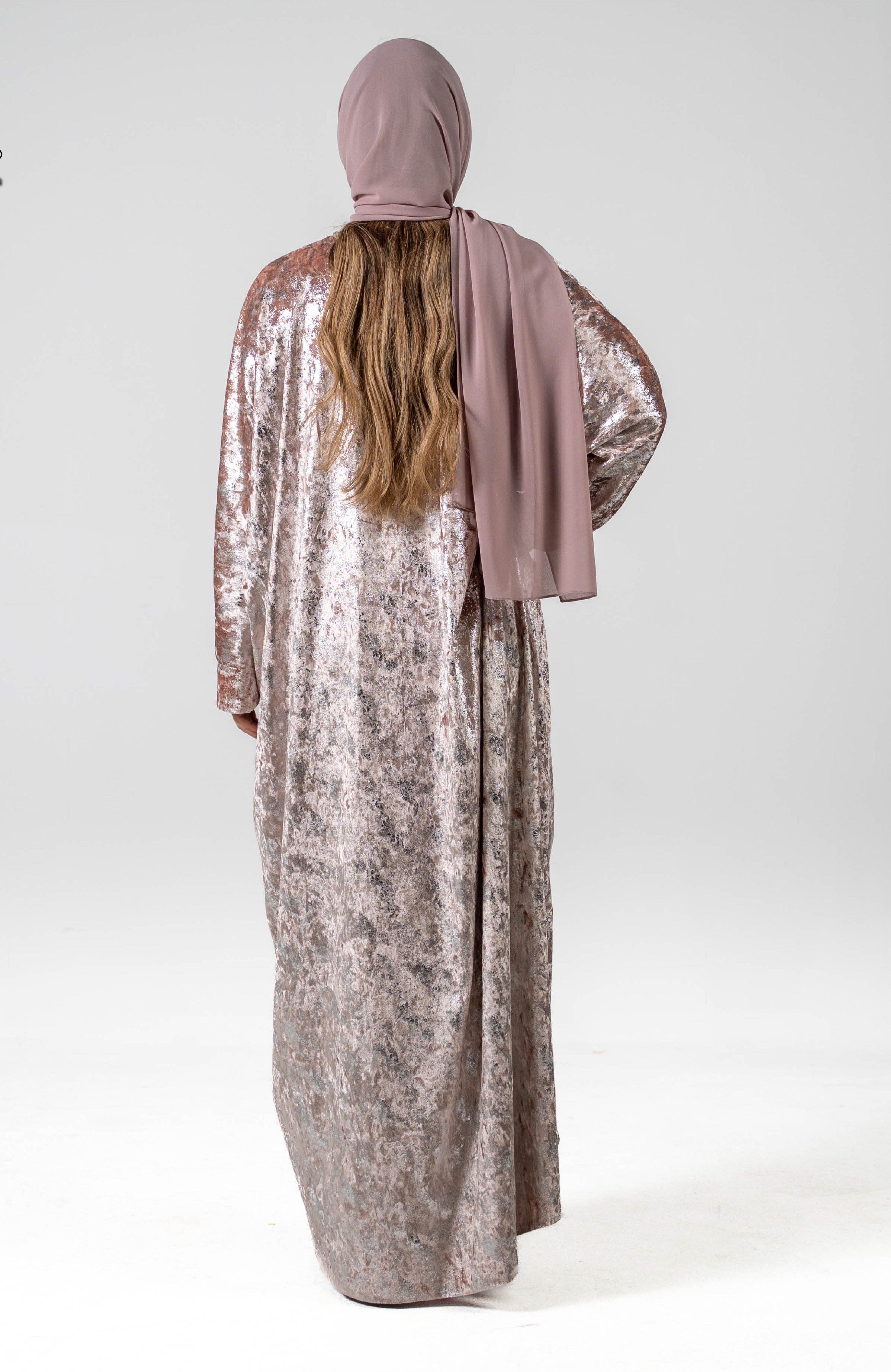 Person wearing a sparkly silver dress and pink hijab on a white background