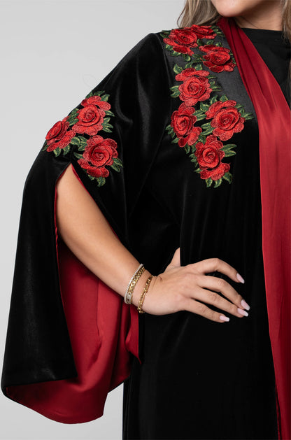 Black garment with red floral embroidery on a plain background