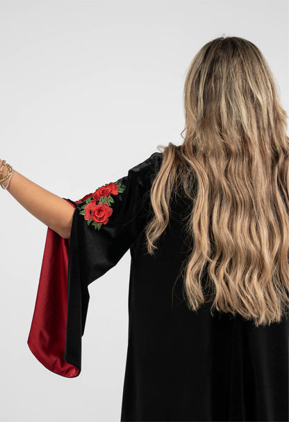Woman wearing a black dress with red sleeves featuring floral designs on a white background