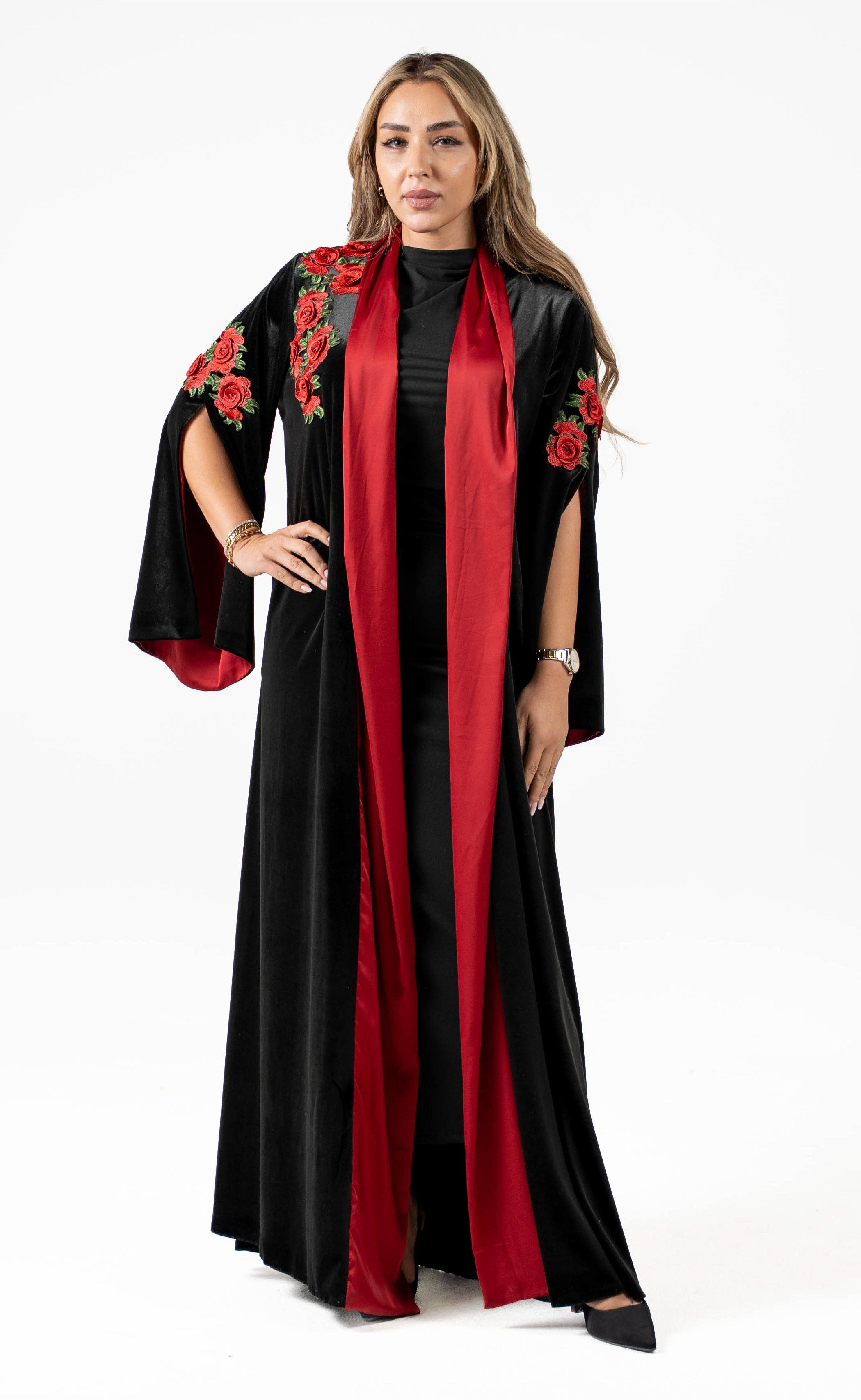 Woman wearing a black and red abaya with floral embroidery on a white background