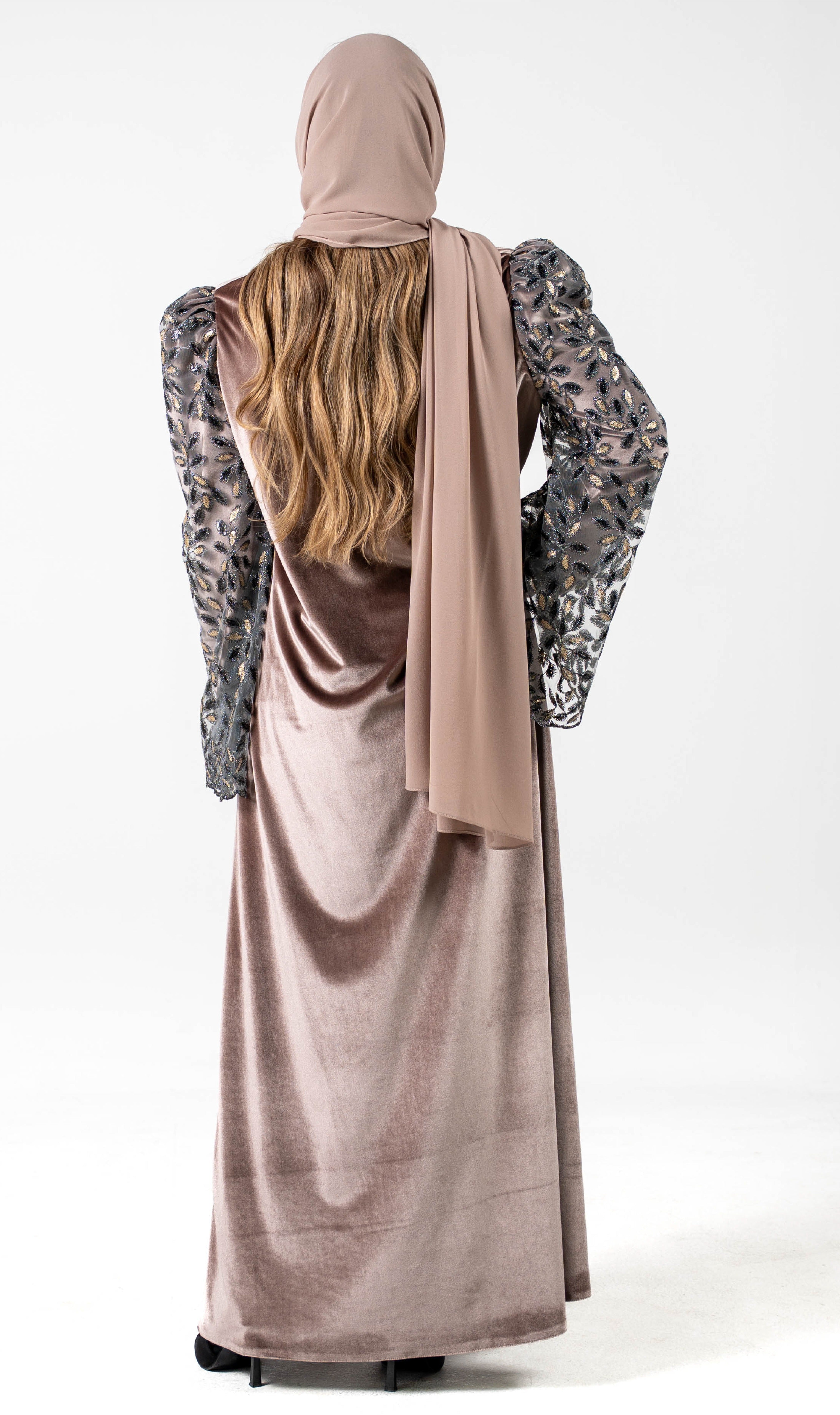 Person wearing a long, light brown dress with a matching hijab on a white background