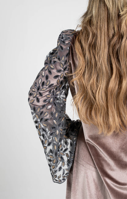 Close-up of a person wearing a patterned long-sleeve top with a plain background