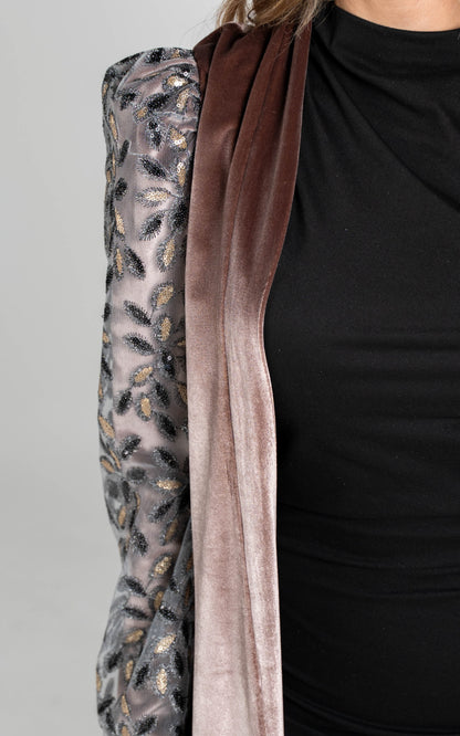 Close-up of a black garment with a brown ribbon and patterned fabric on a gray background