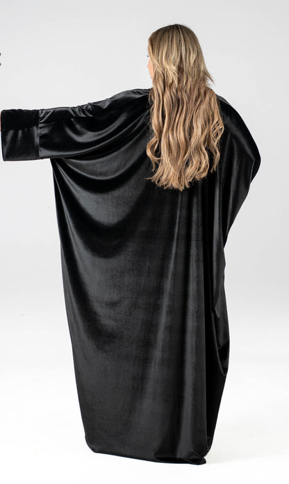 Person wearing a black velvet dress with long sleeves on a white background