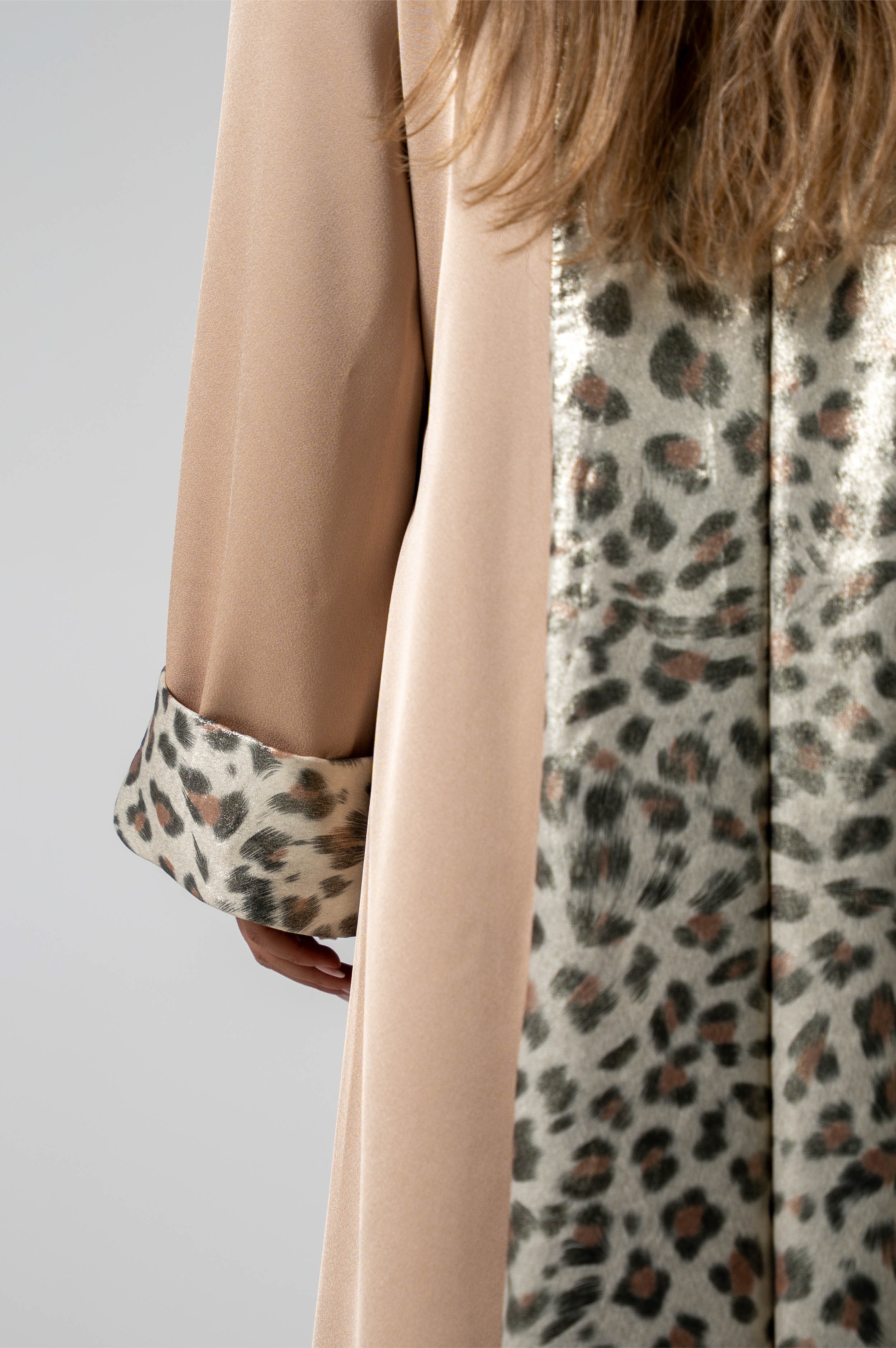 Close-up of a person wearing a beige long-sleeve shirt with leopard print cuffs and collar.