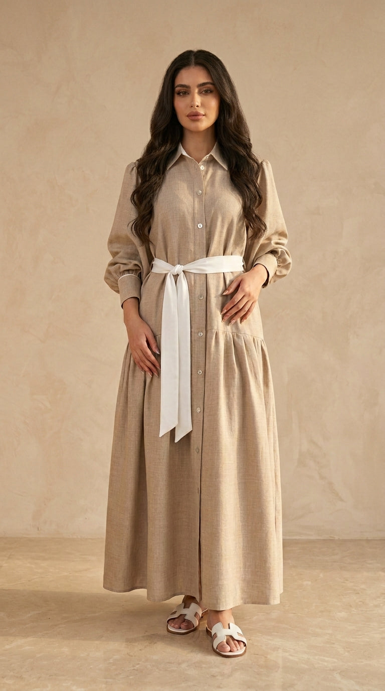 Woman wearing a beige dress with a white belt against a beige background