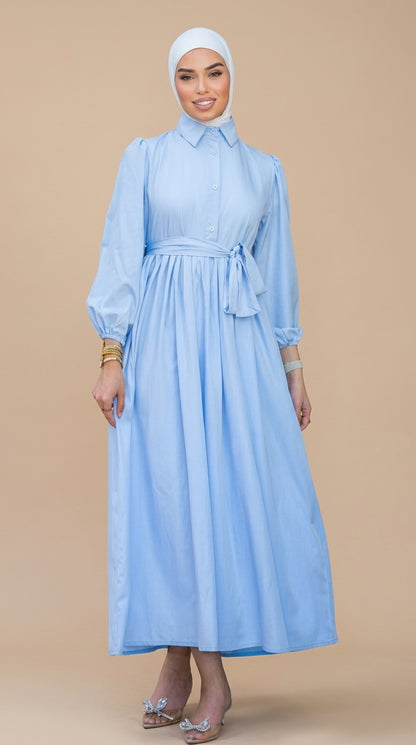 Woman wearing a light blue dress with a belt on a beige background