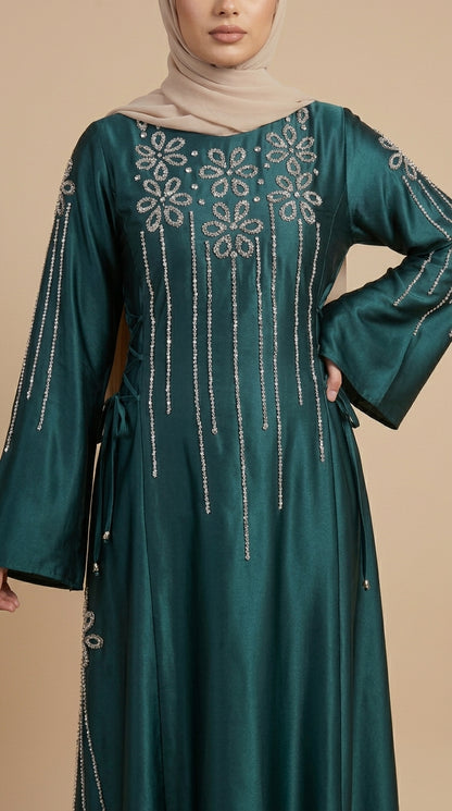 Teal dress with intricate silver embroidery on a beige background