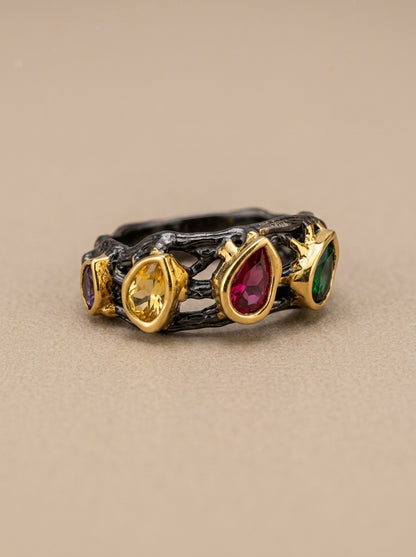 Ring with gold band and multicolored gemstones on a beige background