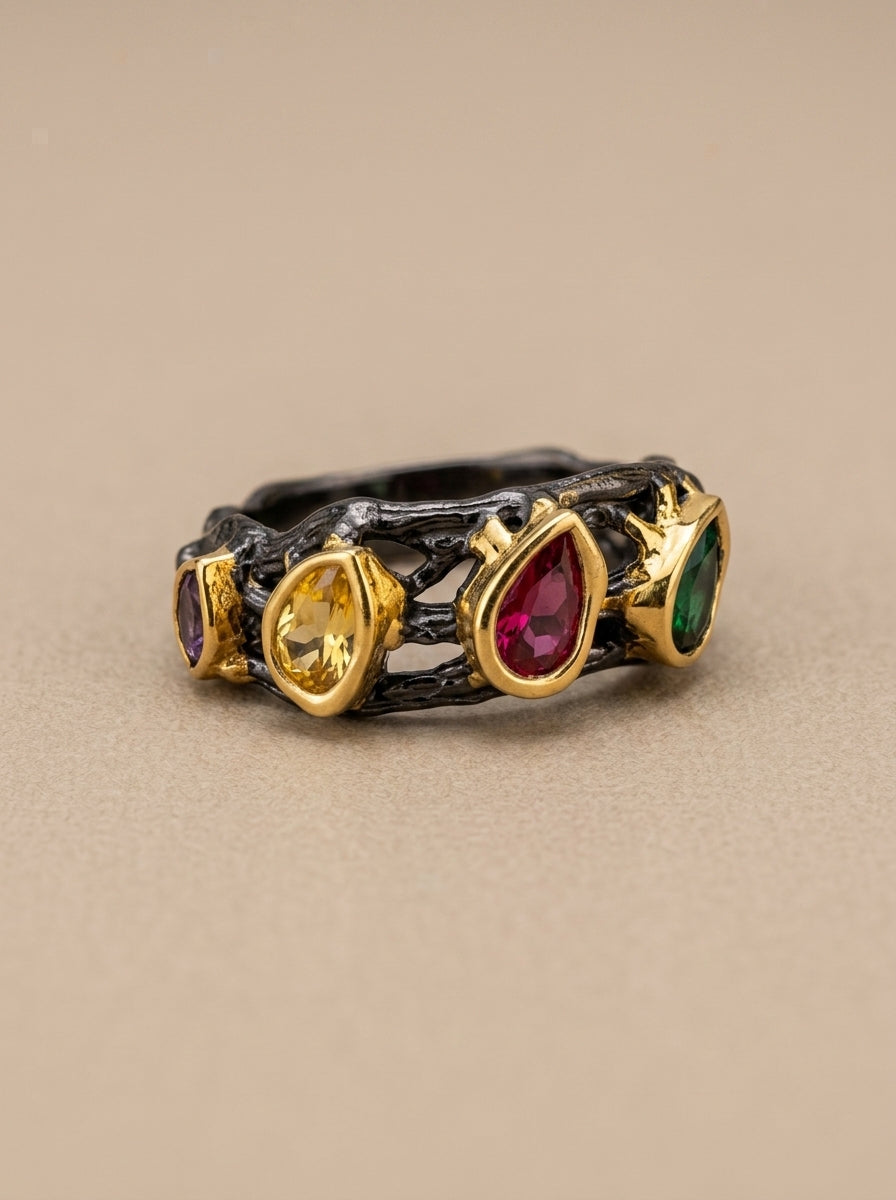 Ring with gold band and multicolored gemstones on a beige background