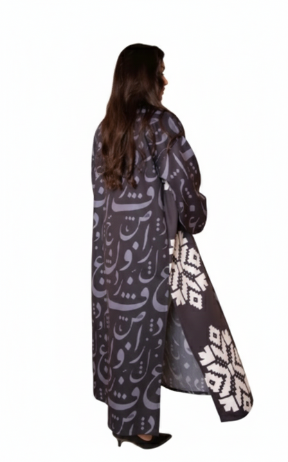 Person wearing a long, dark-colored coat with white patterns on a white background