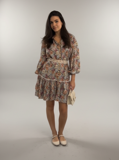 Woman wearing a floral dress with a belt on a plain background