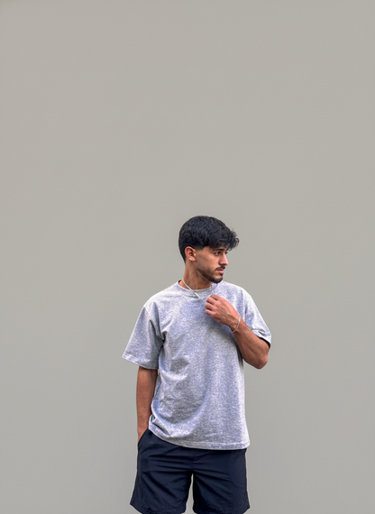 Man wearing a gray t-shirt and dark shorts against a plain background