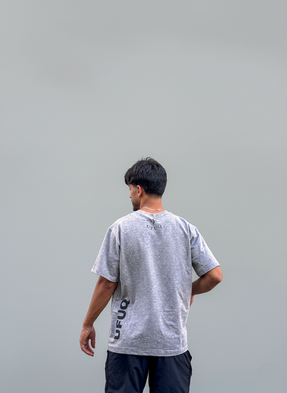 Person wearing a gray t-shirt with text on the back against a plain background