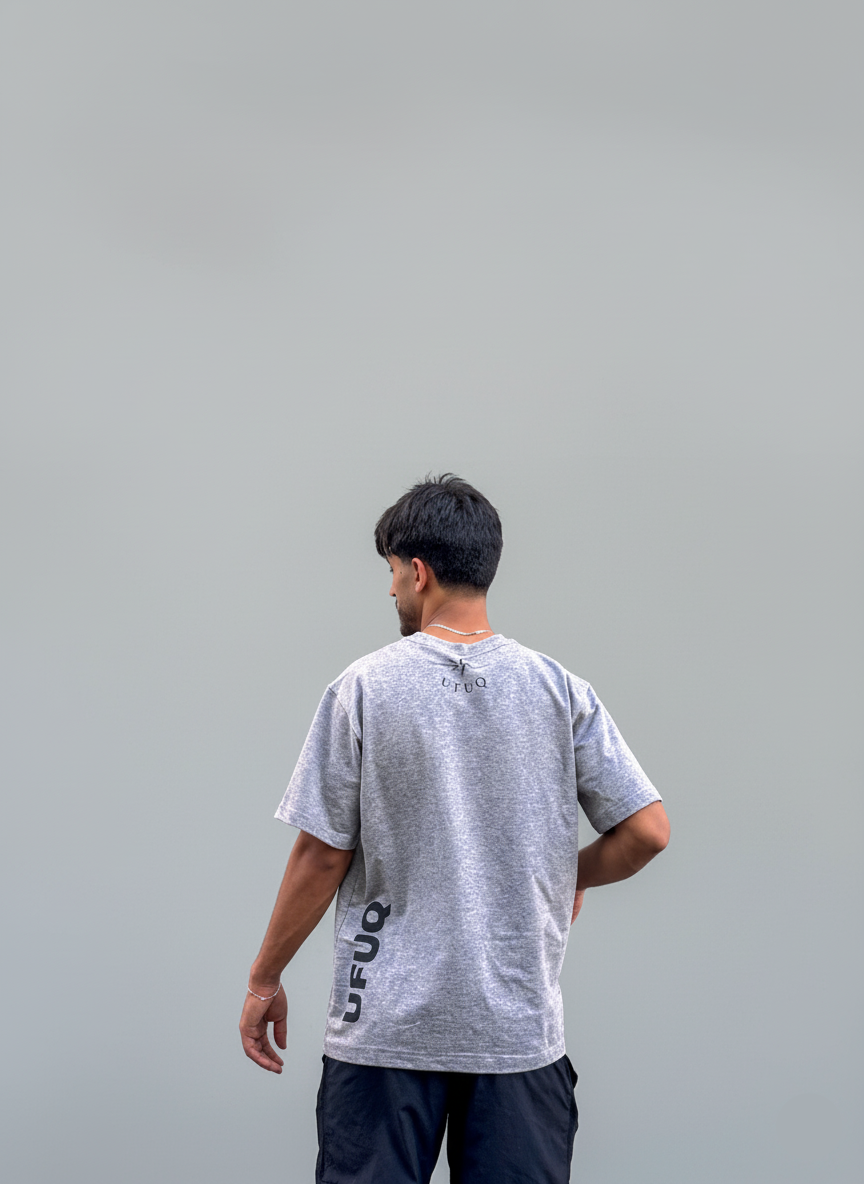Person wearing a gray t-shirt with text on the back against a plain background