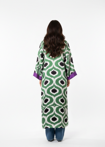 Woman wearing a green patterned dress with purple sleeves on a white background