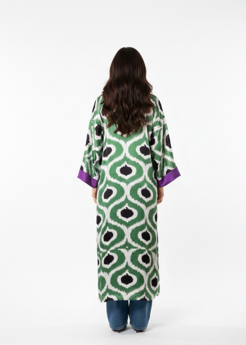 Woman wearing a green patterned dress with purple sleeves on a white background