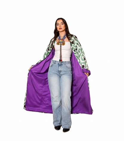 Person wearing a long, patterned coat with a purple lining on a white background
