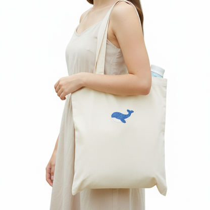 Woman holding a white tote bag with a blue logo on a white background