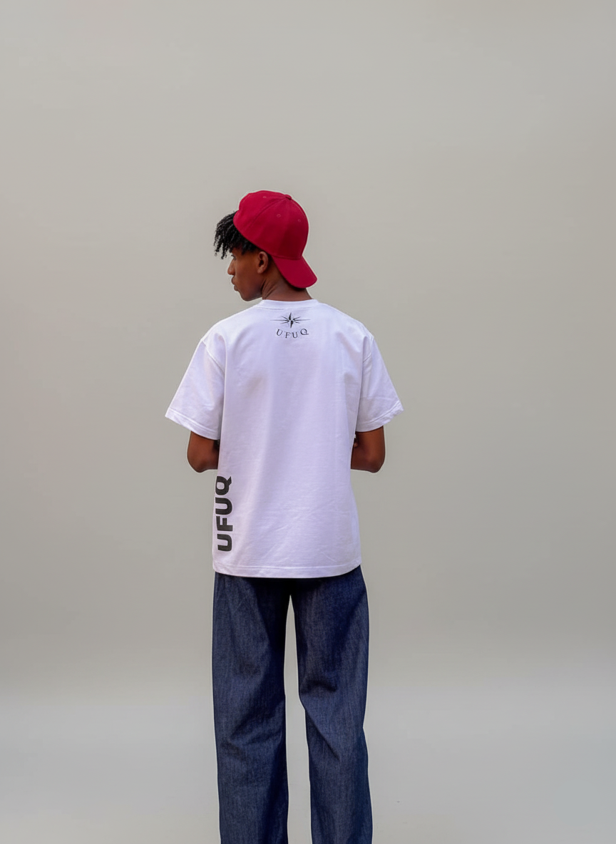 Person wearing a white t-shirt with text and a red cap on a plain background