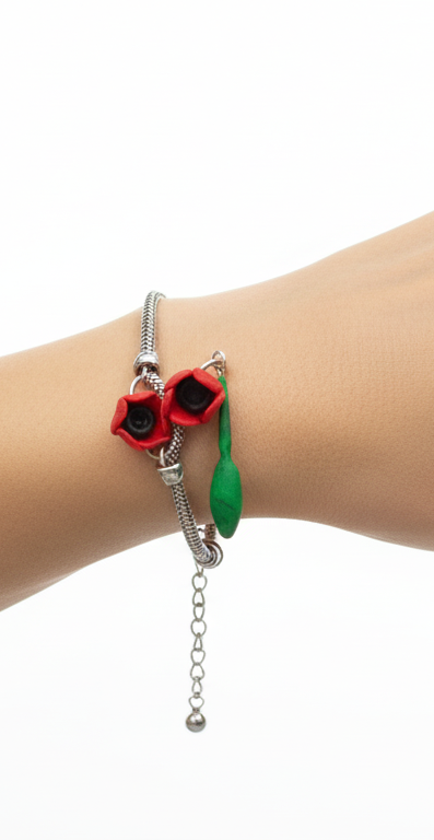 Hand wearing a bracelet with poppy flower charms on a white background